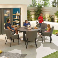 A family of four alfresco dining around. around table and firepit in its centre 